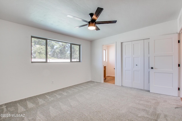 unfurnished bedroom featuring a ceiling fan, a closet, carpet flooring, and ensuite bath