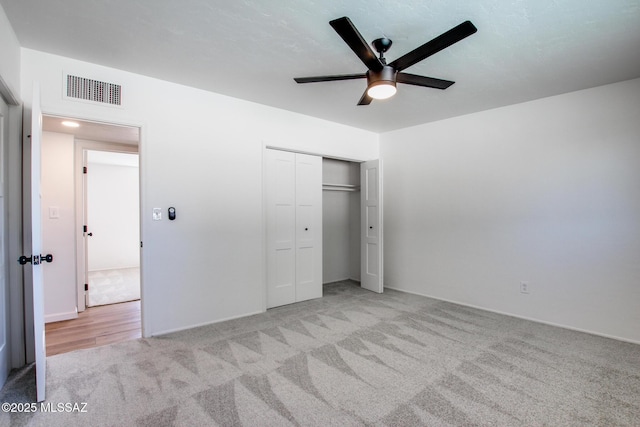 unfurnished bedroom featuring light carpet, ceiling fan, visible vents, and a closet