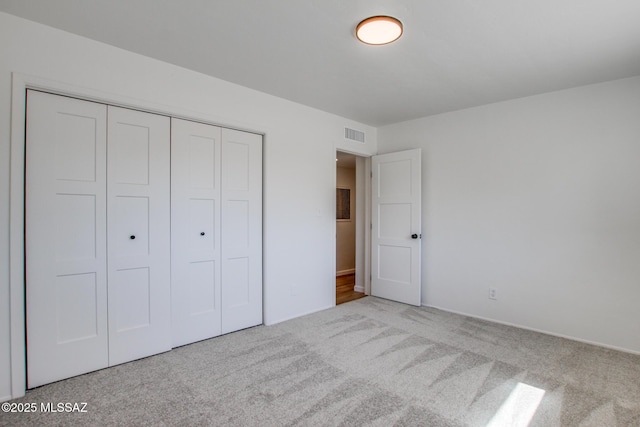 unfurnished bedroom featuring a closet, carpet flooring, and visible vents