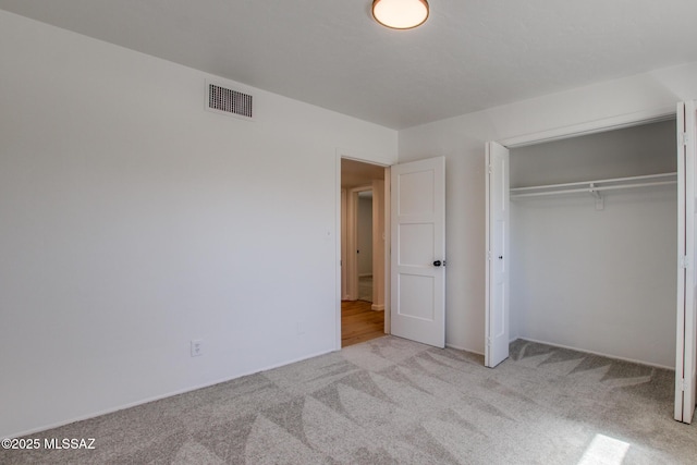 unfurnished bedroom with carpet, a closet, and visible vents