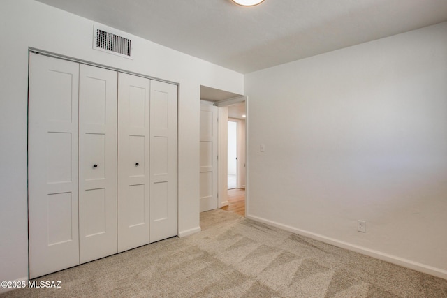 unfurnished bedroom featuring baseboards, carpet, visible vents, and a closet