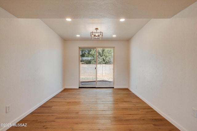 unfurnished room featuring light wood-style floors, baseboards, a notable chandelier, and recessed lighting