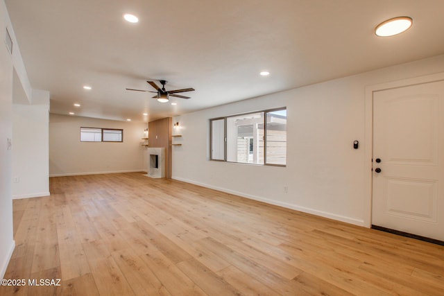 unfurnished living room with light wood-type flooring, recessed lighting, a fireplace, and baseboards