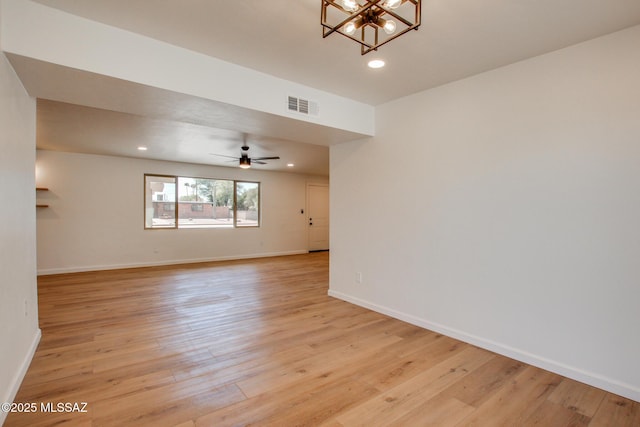 unfurnished room with light wood-type flooring, baseboards, visible vents, and ceiling fan with notable chandelier