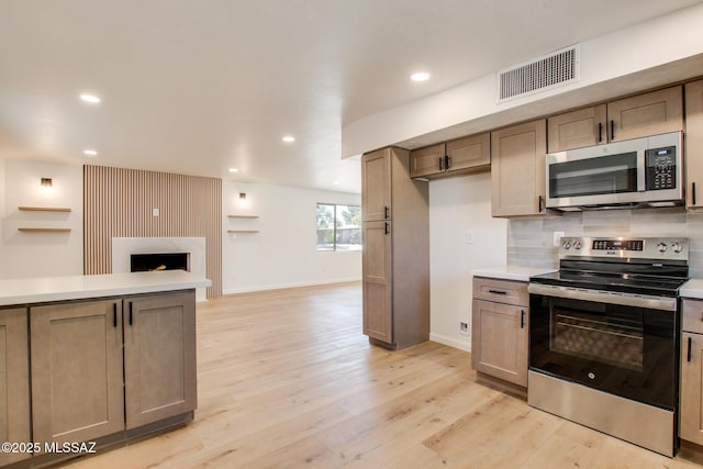 kitchen featuring tasteful backsplash, light countertops, visible vents, appliances with stainless steel finishes, and light wood-style floors