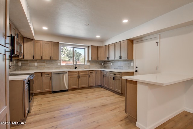 kitchen featuring decorative backsplash, light wood-style flooring, stainless steel appliances, a sink, and recessed lighting