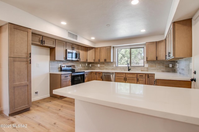 kitchen with tasteful backsplash, visible vents, appliances with stainless steel finishes, light wood-style floors, and a sink