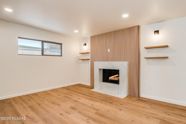 unfurnished living room with a tiled fireplace, recessed lighting, wood finished floors, and baseboards