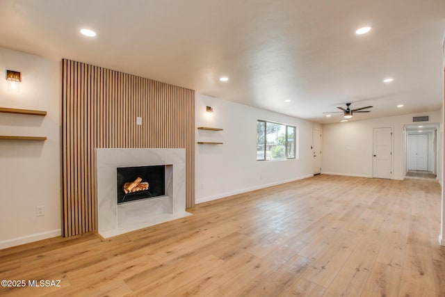 unfurnished living room with recessed lighting, a ceiling fan, wood finished floors, and a high end fireplace