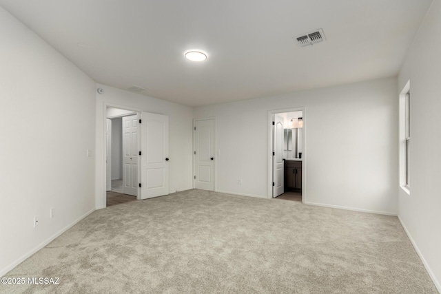 unfurnished bedroom featuring ensuite bath and light carpet