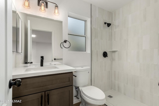 bathroom featuring vanity, tiled shower, and toilet