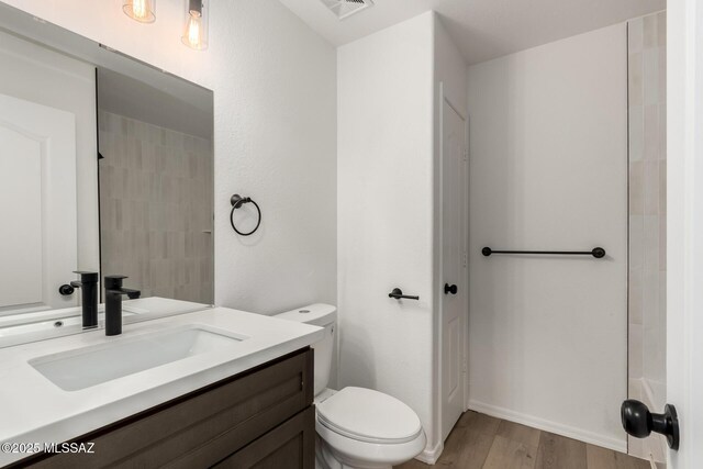 bathroom with hardwood / wood-style flooring, vanity, and toilet