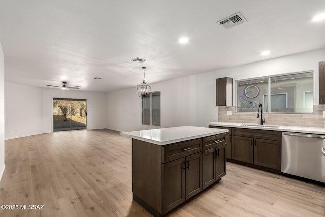 kitchen featuring a kitchen island, dishwasher, sink, backsplash, and light wood-type flooring