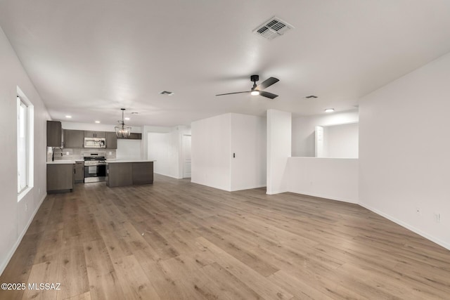 unfurnished living room with sink, ceiling fan with notable chandelier, and wood-type flooring