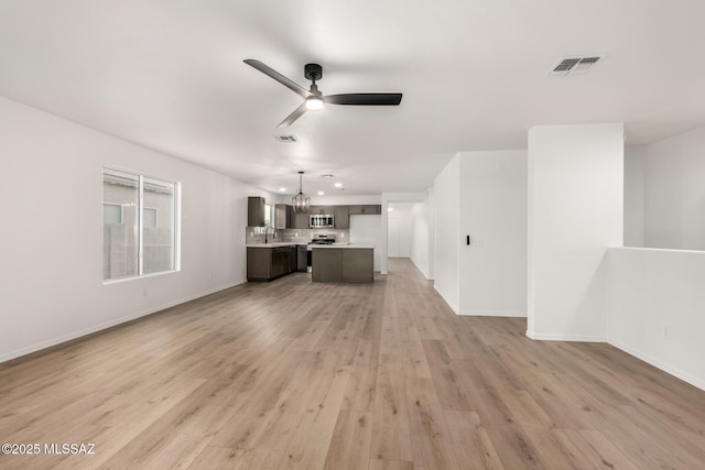 unfurnished living room featuring ceiling fan with notable chandelier, sink, and hardwood / wood-style floors