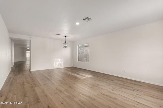 spare room with a notable chandelier and light hardwood / wood-style flooring