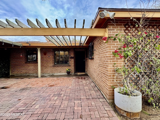 property entrance featuring brick siding and a pergola