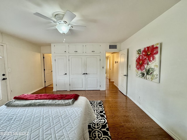 bedroom featuring a ceiling fan, wood finished floors, visible vents, and baseboards