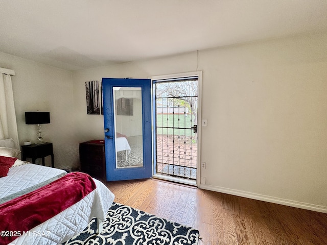 bedroom featuring access to exterior, baseboards, and wood finished floors