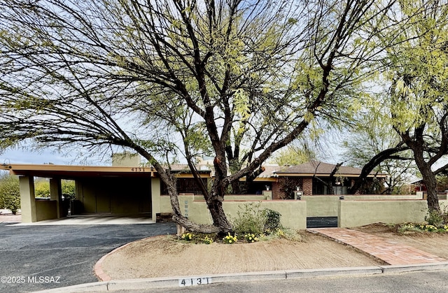 single story home with a fenced front yard, aphalt driveway, and brick siding