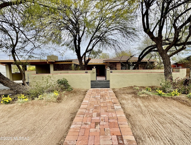 ranch-style home featuring a gate, a fenced front yard, and stucco siding