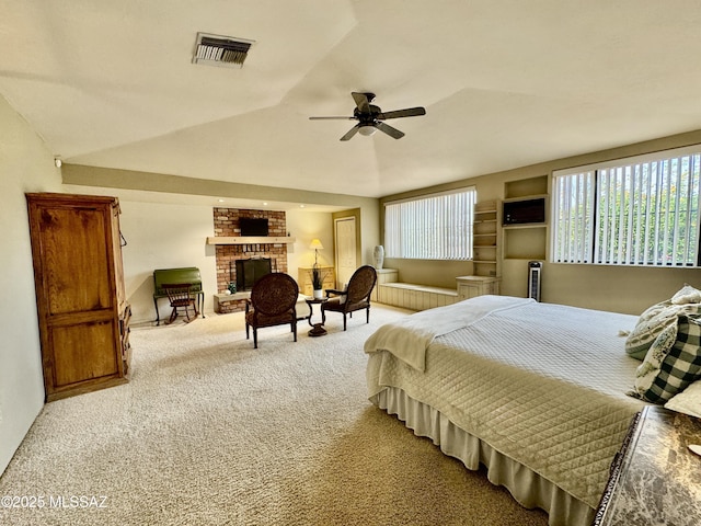 carpeted bedroom featuring a brick fireplace, visible vents, vaulted ceiling, and a ceiling fan