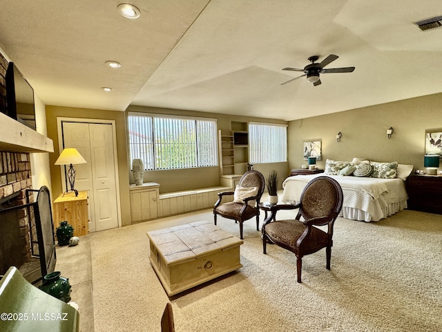 carpeted bedroom with a closet, visible vents, a fireplace, and ceiling fan