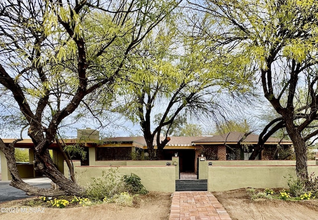 ranch-style house with a fenced front yard and brick siding