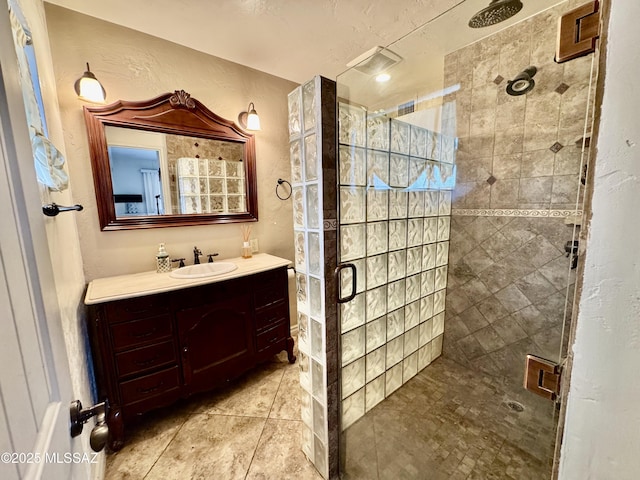 bathroom featuring a textured wall, a shower stall, tile patterned flooring, and vanity