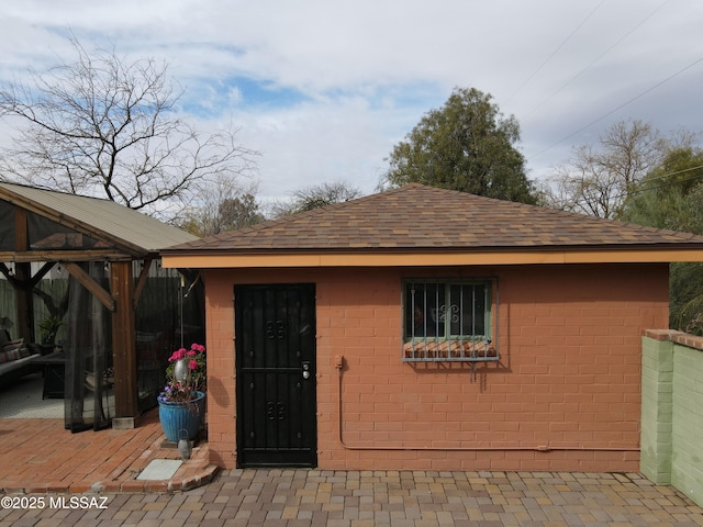 property entrance with a shingled roof and brick siding