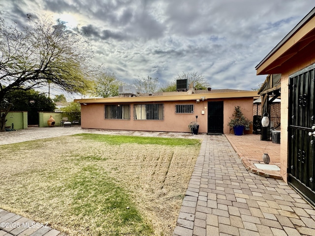 exterior space featuring central air condition unit, a patio area, a yard, and stucco siding