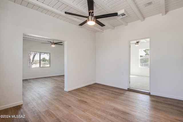 empty room with light hardwood / wood-style flooring, beam ceiling, and plenty of natural light