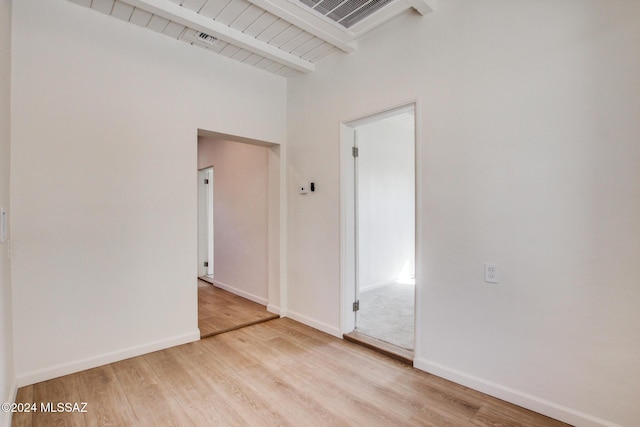 spare room with beamed ceiling, wood ceiling, and light hardwood / wood-style floors