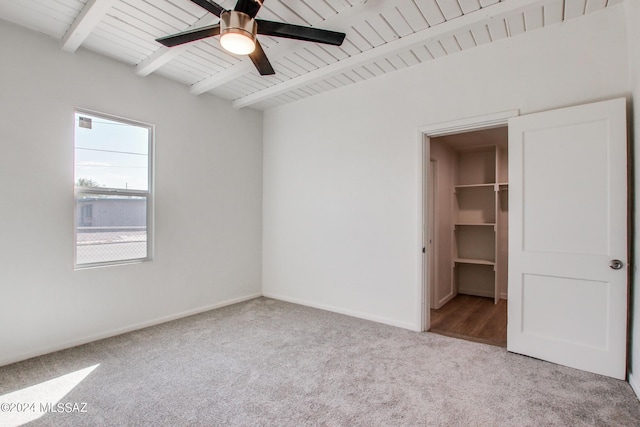 unfurnished bedroom with a spacious closet, light colored carpet, wooden ceiling, beam ceiling, and a closet