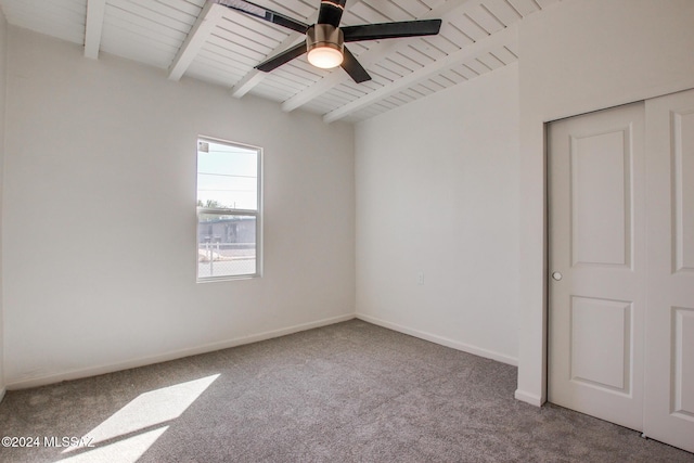 carpeted spare room featuring ceiling fan, wooden ceiling, and beamed ceiling