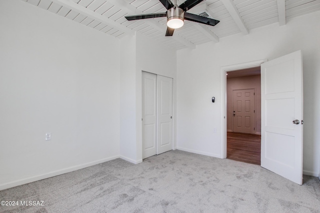 unfurnished bedroom featuring light carpet, wooden ceiling, and beamed ceiling