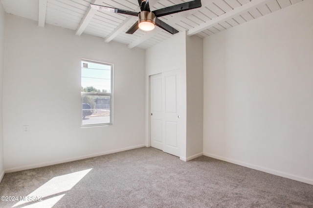 carpeted spare room featuring lofted ceiling with beams and ceiling fan