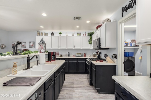 kitchen with white cabinetry, sink, washer / dryer, and appliances with stainless steel finishes