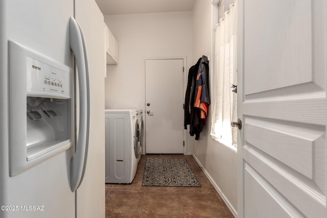 washroom featuring cabinets, washing machine and dryer, and dark tile patterned flooring