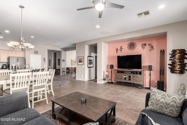 living room with ceiling fan with notable chandelier and tile patterned floors