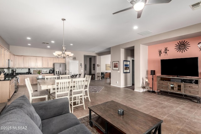 tiled living room with sink and ceiling fan with notable chandelier