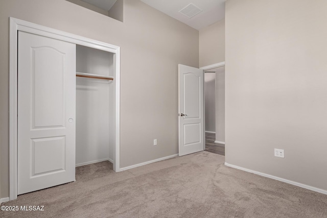 unfurnished bedroom featuring light colored carpet and a closet