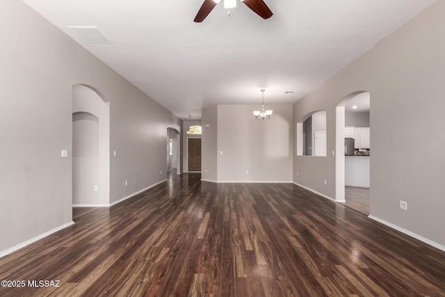 unfurnished living room with ceiling fan with notable chandelier and dark hardwood / wood-style flooring