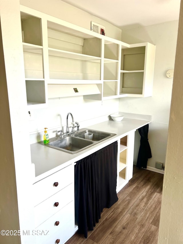 kitchen featuring dark wood-type flooring, sink, and white cabinets