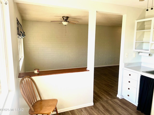 interior space with sink, a textured ceiling, dark hardwood / wood-style floors, ceiling fan, and brick wall