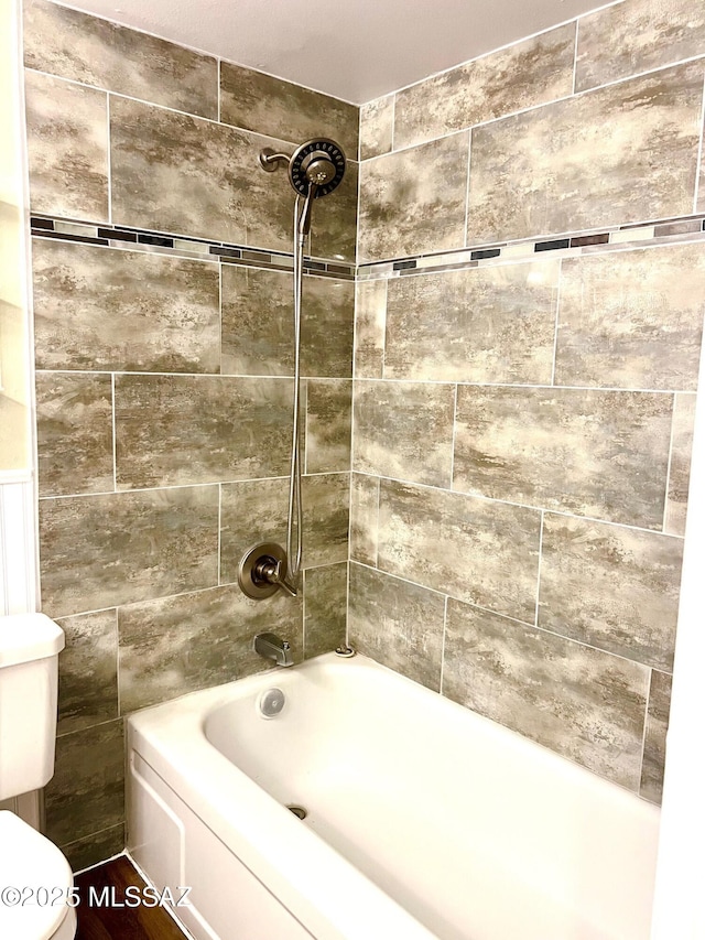 bathroom with tiled shower / bath combo and toilet