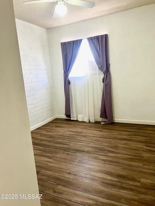 spare room featuring dark wood-type flooring, ceiling fan, and a textured ceiling