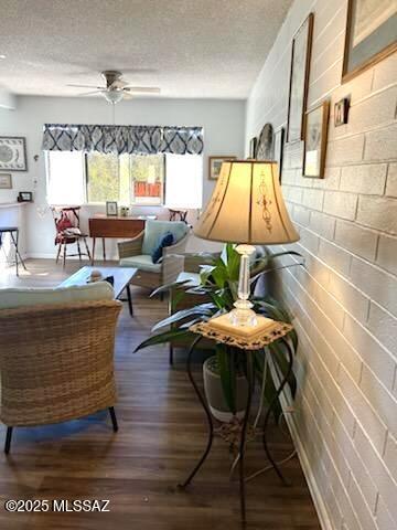 living area with hardwood / wood-style flooring, ceiling fan, and a textured ceiling