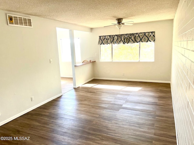 unfurnished room featuring ceiling fan, dark hardwood / wood-style floors, and a textured ceiling