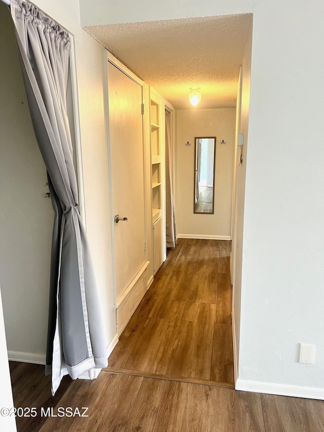 corridor with hardwood / wood-style floors and a textured ceiling